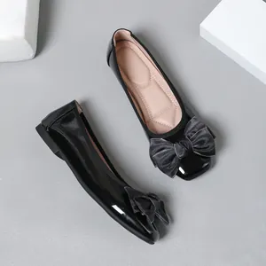 Top-down view of black patent leather ballet flats featuring an elegant satin bow detail