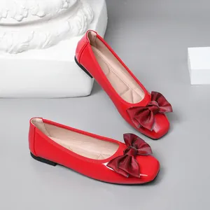 Detailed view of red patent leather ballet flats with large maroon bows and square toes