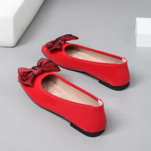 Detail view of elegant red patent ballet flats featuring a large decorative bow on the toe