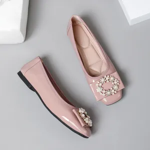 Detailed view of pink patent leather ballet flats with square toe and pearl buckle