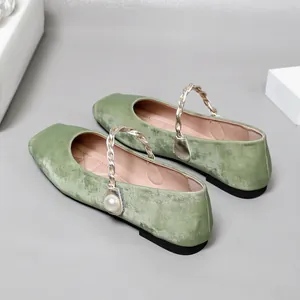 Detailansicht grüner Samt Mary Janes mit elegantem Goldflechtriemen und Perlendetail.