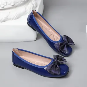 Close-up of blue patent leather ballet flats with a stylish chiffon bow detail