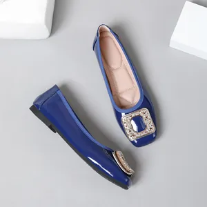 Detail view of blue patent leather square toe flats with a shiny rhinestone buckle.