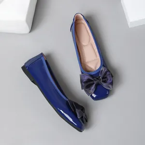Close-up detail of dark blue patent leather ballet flats featuring a large elegant bow