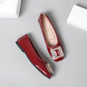 Close-up of burgundy patent leather flats with elegant and shiny crystal buckle