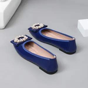 Close-up view of blue patent leather ballet flats with elegant pearl buckle decoration