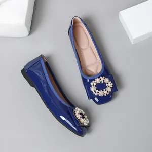 Close-up of elegant blue patent leather ballet flats featuring a decorative pearl buckle