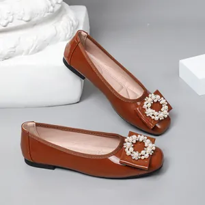 Detailed view of brown patent leather ballet flats with elegant pearl buckles.