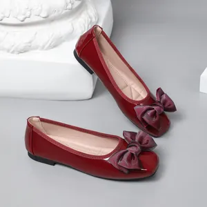 Detailed view of red patent leather ballet flats featuring elegant bow decoration