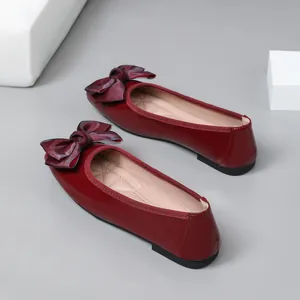 Close-up of wine red glossy ballet flats featuring a decorative bow and pointed toe design