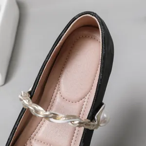 Nahaufnahme von Perlenakzent und Kettenschlaufe an schwarzen Mary Jane Ballerinas