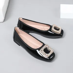 Detail view of black patent leather ballet flats with sparkling rhinestone buckle