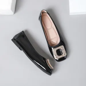 Detail of shiny black patent leather flats with elegant rhinestone square buckle