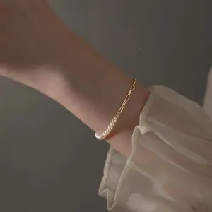 Detail view of elegant Korean style pearl and gold geometric chain bracelet on female wrist