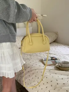 Vista lifestyle di una borsa a cuscino gialla tenuta da una donna in una camera