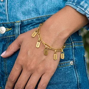 Bracelet à maillons dorés avec noms gravés personnalisés sur un fond en jean bleu.