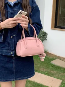 Elegante borsa a bauletto rosa in ecopelle indossata con un outfit casual in denim