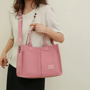 Detalle de bolso tote de lona rosa con múltiples bolsillos y cómoda correa ancha