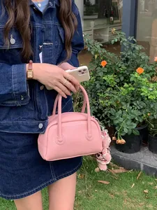 Donna tiene una borsa a cuscino rosa in pelle martellata con un dolce ciondolo a orso.