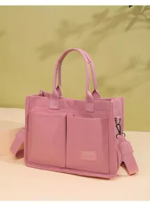 Bolso tote grande de lona rosa equipado con varios bolsillos y una correa ancha.