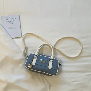 Detailed view of a blue denim bowling bag with white trim and gold lock charm