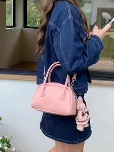 Borsa a bauletto in pelle rosa con manici e un ciondolo a forma di peluche