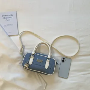 Denim bowling handbag with white faux leather trim and a stylish mini lock charm detail.