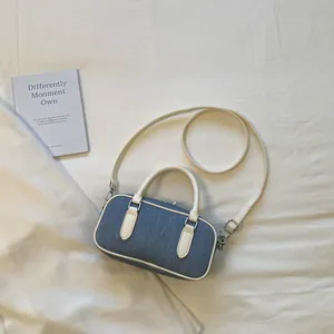 Top view of a stylish blue denim Boston bag with white faux leather handles and strap.