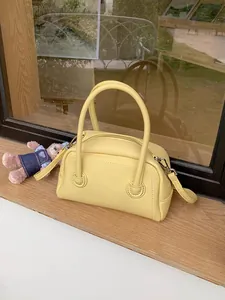 Dettaglio di una borsa a cuscino in pelle gialla testurizzata su davanzale in legno