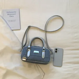 Stylish grey denim Boston bag with silver handles and lock charm detail in flat lay