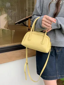 Vista ravvicinata di una borsa a bauletto in pelle martellata gialla tenuta da una modella