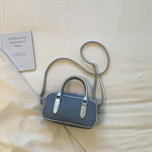 Detail view of denim bowling bag with metallic silver handles and adjustable strap