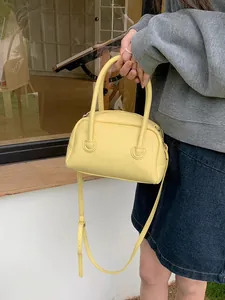 Dettaglio di una borsa a cuscino in pelle gialla tenuta da una persona all'aperto