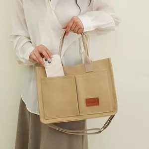 Primer plano de un gran bolso tote de lona con un bolsillo frontal para el móvil.