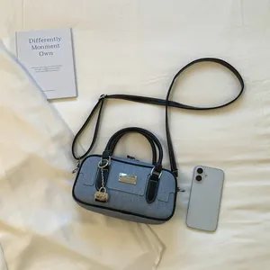 Blue denim Boston bowling bag with black handles shown beside a smartphone for scale.