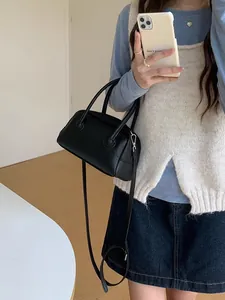 Elegante borsa a cuscino in ecopelle martellata nera con tracolla indossata da una modella