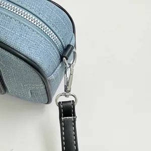 Close-up of blue denim bowling bag showing silver zipper and black strap detail