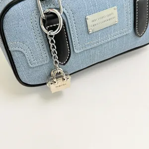 Close-up of light blue denim Boston bag with silver hardware and fashion charm