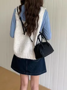 Modella indossa una borsa a bauletto nera in pelle martellata a tracolla classica