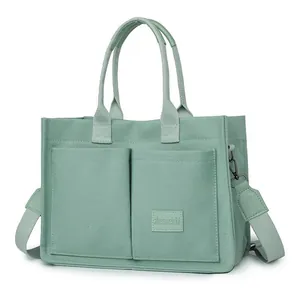 Detalle del bolso tote de lona verde salvia con múltiples bolsillos y correa ancha