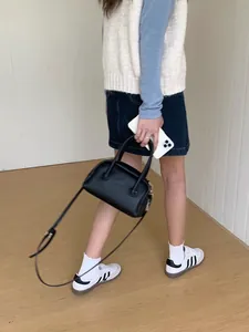 Elegante borsa a cuscino nera minimalista mostrata in una posa chic in stile di vita urbano