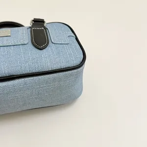 Close-up of blue denim bowling bag featuring black leather piping and detailed stitching.