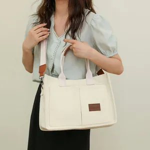 Bolso tote de lona beige de gran capacidad con bolsillos y correa ancha