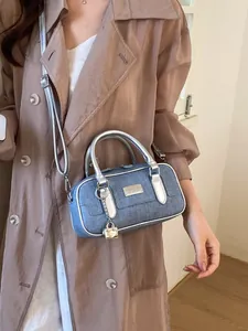 Stylish blue denim bowling bag with silver leather trim and adjustable crossbody strap for women