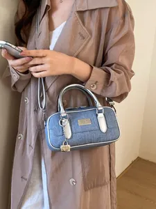Blue denim bowling bag with silver handles and adjustable strap for casual style