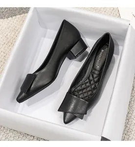 Escarpins noirs élégants à bout pointu et talon carré dans une boîte à chaussures blanche.