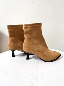Detailansicht stilvoller brauner Wildleder-Stiefeletten mit spitzer Zehenpartie und Pfennigabsatz.