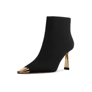 Sleek black ankle boot featuring a pointed gold toe cap and metallic stiletto heel.