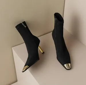 Detail view of black high heel stretch boots featuring an elegant gold metal square toe