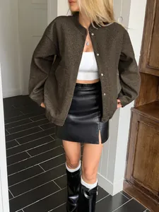 Detailed view of women's brown oversized jacket styled with black leather mini skirt